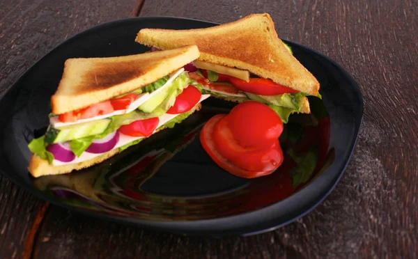 Sandwich vegetariano con tomate en un plato negro — Foto de Stock