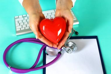 Kadın doktor kalp tutan stetoskop ile. Doktor ve hasta arka planda oturan