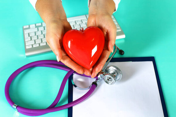 Женщина-врач со стетоскопом, держащая сердце. Врач и пациент сидят на заднем плане
