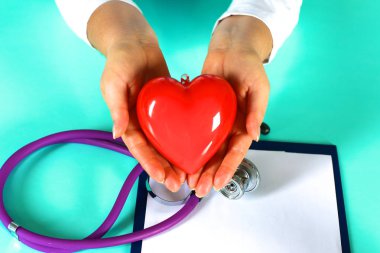 Kadın doktor kalp tutan stetoskop ile. Doktor ve hasta arka planda oturan