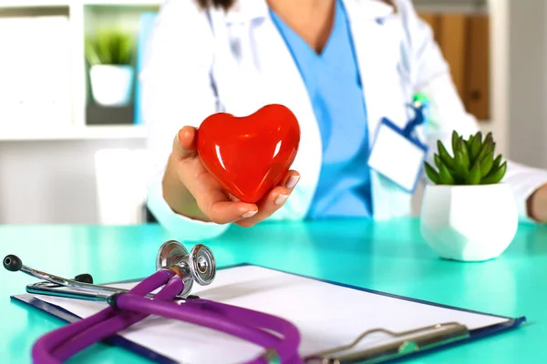 Woman doctor with a stethoscope holds a heart — Stock Photo, Image