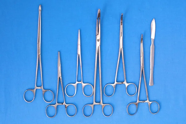 Ameliyat için masaya yerleştirilmiş neşter, pens ve cımbız gibi cerrahi aletler ve aletler. — Stok fotoğraf