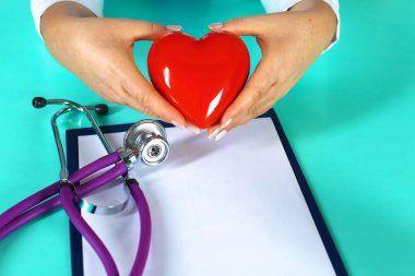 Kadın doktor kalp tutan stetoskop ile. Doktor ve hasta arka planda oturan