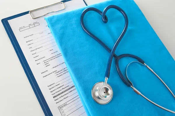 Estetoscopio en una mesa con uniforme médico —  Fotos de Stock