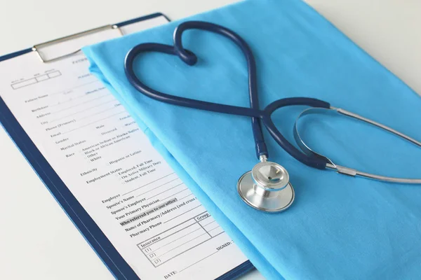 Estetoscopio en una mesa con uniforme médico — Foto de Stock