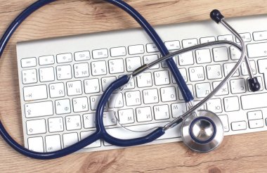 Beyaz ahşap bir masa üstünde a laptop yanında sağlık stetoskop