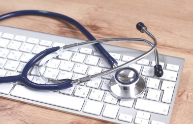 Beyaz ahşap bir masa üstünde a laptop yanında sağlık stetoskop