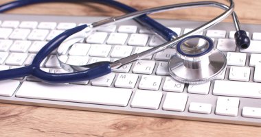 Beyaz ahşap bir masa üstünde a laptop yanında sağlık stetoskop
