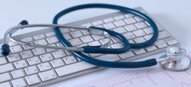 Bir dizüstü bilgisayarda masada beyaz yakınındaki tıbbi bir stetoskop