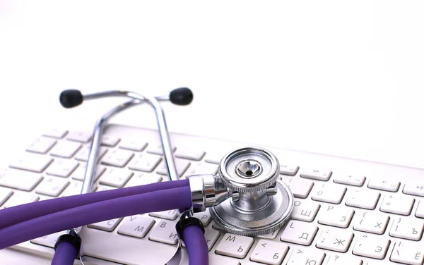 Lékařský fonendoskop poblíž laptop na stole, na bílém pozadí — Stock fotografie