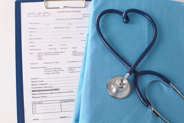 Un stéthoscope façonnant un cœur sur un uniforme médical, gros plan — Photo