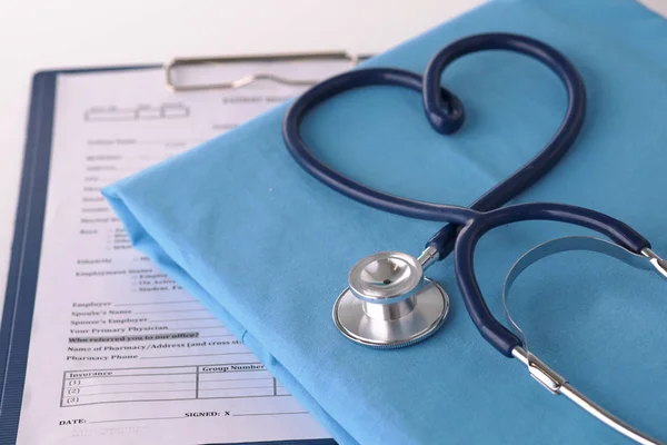 Um estetoscópio moldando um coração em um uniforme médico, close-up — Fotografia de Stock