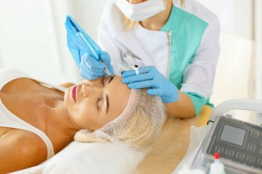 Kalıcı makyaj kaşları için. Güzellik Salonu içinde kalın kaşları ile güzel bir kadın. Şevval Özçelik Güzellik kadın yüzü için kaş dövme yapıyor. Güzellik yordamı