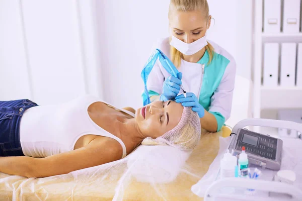 Maquillaje permanente para las cejas. Hermosa mujer con cejas gruesas en salón de belleza. esteticista haciendo tatuajes de cejas para la cara femenina. Procedimiento de belleza — Foto de Stock