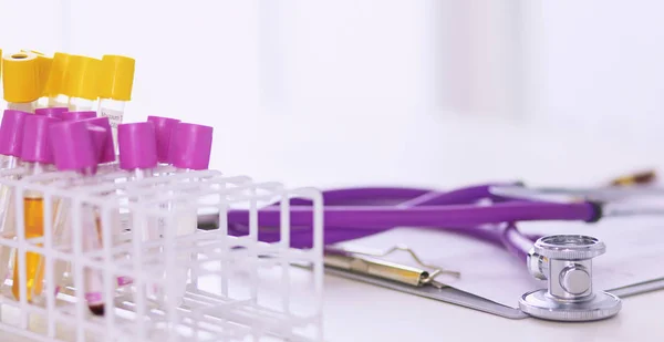 Closeup of the desk of a doctors office with a stethoscope in the foreground and a bottle with pills in the background — Stock Photo, Image