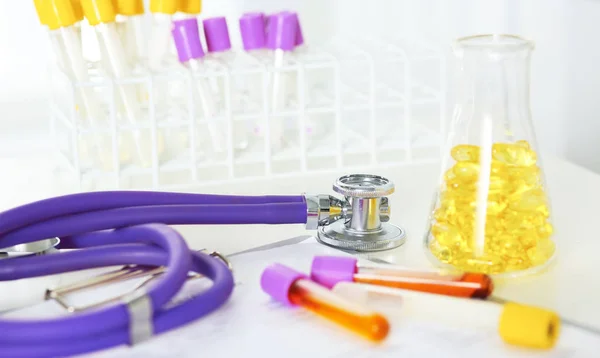 Primer plano del escritorio de un consultorio médico con un estetoscopio en primer plano y una botella con pastillas en el fondo — Foto de Stock