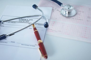 Doktorların çalışma alanı çalışma tablosu hastalar deşarj boş kağıt formu, tıbbi reçete, stetoskop üstünde okul sırası ile