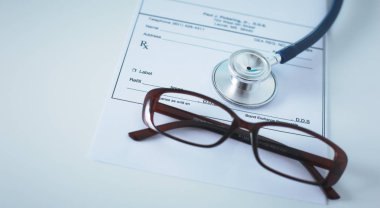 Doktorların çalışma alanı çalışma tablosu hastalar deşarj boş kağıt formu, tıbbi reçete, stetoskop üstünde okul sırası ile