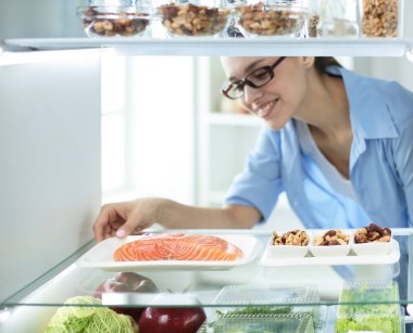 Mutlu kadın açık buzdolabı önünde sebzeli
