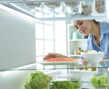 Mutlu kadın açık buzdolabı önünde sebzeli