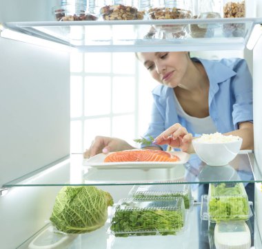 Mutlu kadın açık buzdolabı önünde sebzeli