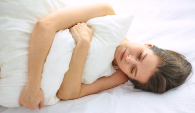 Genç güzellik beyaz bir yatakta uyuyor