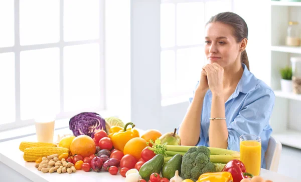 Glad Ung hemmafru sitter i köket förbereder mat från en hög med olika färska ekologiska frukter och grönsaker — Stockfoto