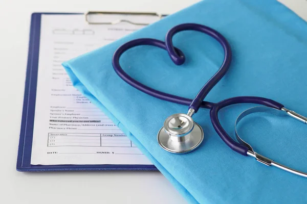 Estetoscopio en una mesa con uniforme médico — Foto de Stock