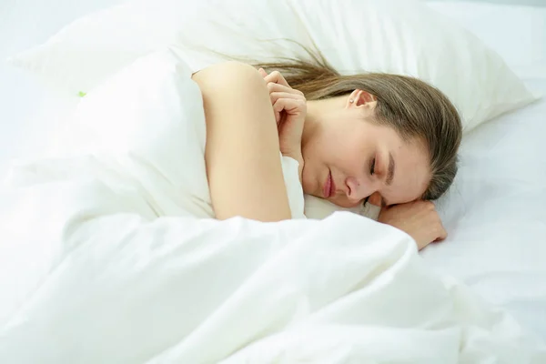 Unga skönhet somna i en vit säng — Stockfoto
