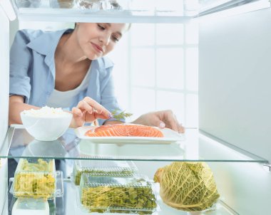 Mutlu kadın açık buzdolabı önünde sebzeli