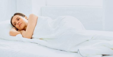 Genç güzellik beyaz bir yatakta uyuyor