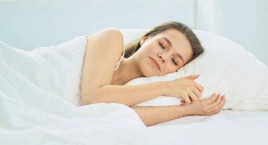 Genç güzellik beyaz bir yatakta uyuyor