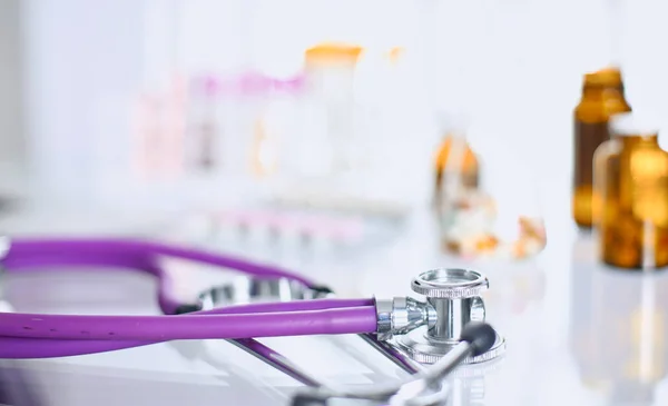 Close-up van de balie van een kantoor van de artsen met een stethoscoop op de voorgrond en een fles met pillen in de achtergrond — Stockfoto