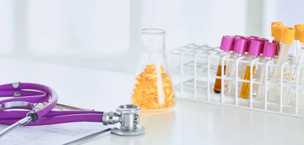 Крупним планом стіл лікаря кабінету зі стетоскопом на передньому плані і пляшкою з таблетками на задньому плані — стокове фото