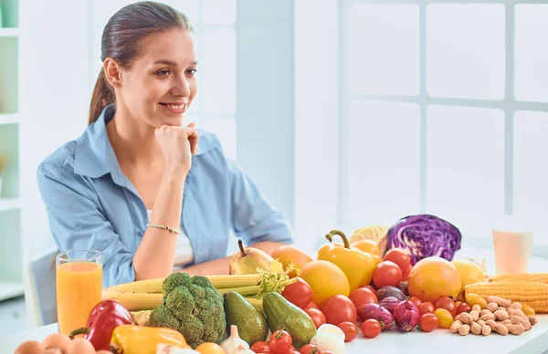 Glad Ung hemmafru sitter i köket förbereder mat från en hög med olika färska ekologiska frukter och grönsaker — Stockfoto