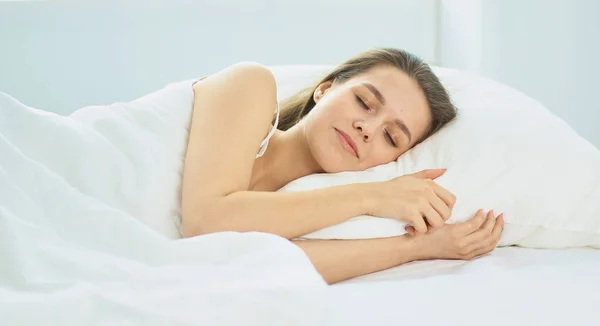 Unga skönhet somna i en vit säng — Stockfoto