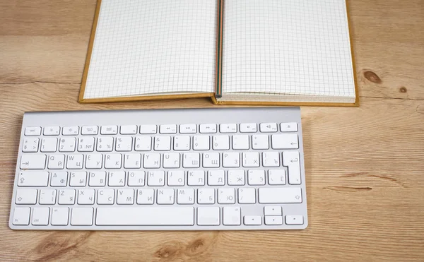 コンピューターのキーボードとノートが机の上 — ストック写真