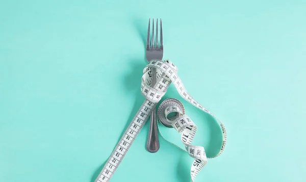 El tenedor se envuelve con una cinta métrica sobre la mesa. Dieta — Foto de Stock
