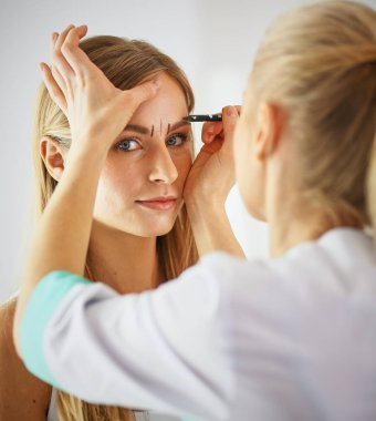 Kalıcı makyaj kaşları için. Güzellik Salonu içinde kalın kaşları ile güzel bir kadın. Şevval Özçelik Güzellik kadın yüzü için kaş dövme yapıyor. Güzellik yordamı, seçici odak