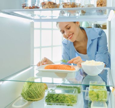 Mutlu kadın ile sebze önünde açık buzdolabı, seçici odak