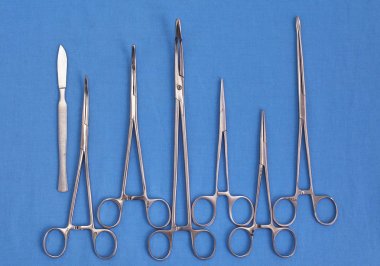 Ameliyat için masaya yerleştirilmiş neşter, pens ve cımbız gibi cerrahi aletler ve aletler.