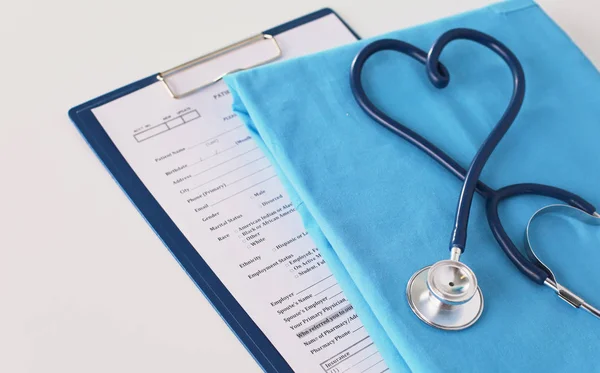 Um estetoscópio moldando um coração em um uniforme médico, close-up, foco seletivo — Fotografia de Stock