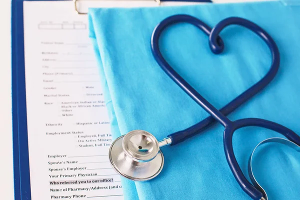 Un estetoscopio dando forma a un corazón en un uniforme médico, primer plano, enfoque selectivo —  Fotos de Stock