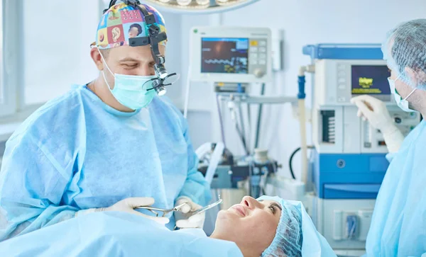 Plusieurs médecins entourant le patient sur la table d'opération pendant leur travail. Chirurgiens d'équipe au travail en salle d'opération — Photo