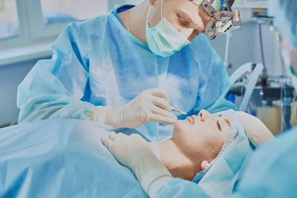 Plusieurs médecins entourant le patient sur la table d'opération pendant leur travail. Chirurgiens d'équipe au travail en salle d'opération — Photo