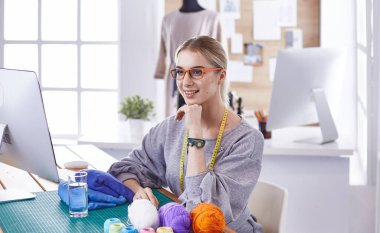 Masasında dikiş makinesi olan bir fabrikada genç ve güzel bir kız.