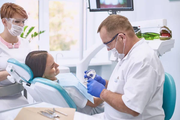 Médico dentista trata os dentes de uma bela jovem paciente. A rapariga na recepção do dentista. Médico dentista trata dente — Fotografia de Stock