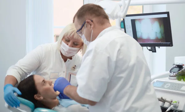 Doctor dentist treats teeth of a beautiful young girl patient. The girl on reception at the dentist. Doctor dentist treats tooth Stock Picture