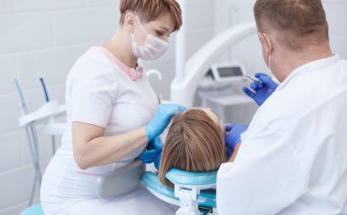 Doktor dişçi genç ve güzel bir kızın dişlerini tedavi ediyor. Dişçinin resepsiyonundaki kız. Doktor dişçi dişleri tedavi eder.