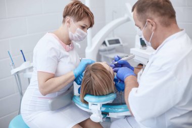 Doktor dişçi genç ve güzel bir kızın dişlerini tedavi ediyor. Dişçinin resepsiyonundaki kız. Doktor dişçi dişleri tedavi eder.